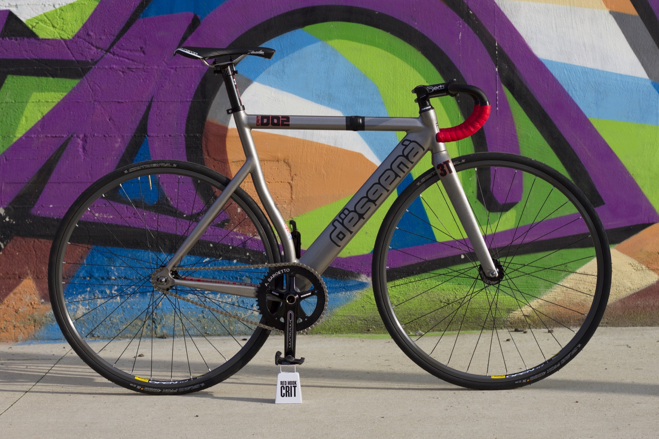 dësgenà track bike against a graffiti wall